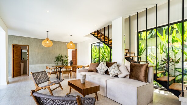 A modern living room with a sofa, chairs, a coffee table, and a staircase with a view of greenery. - Joy Villa by Betterplace (Canggu)