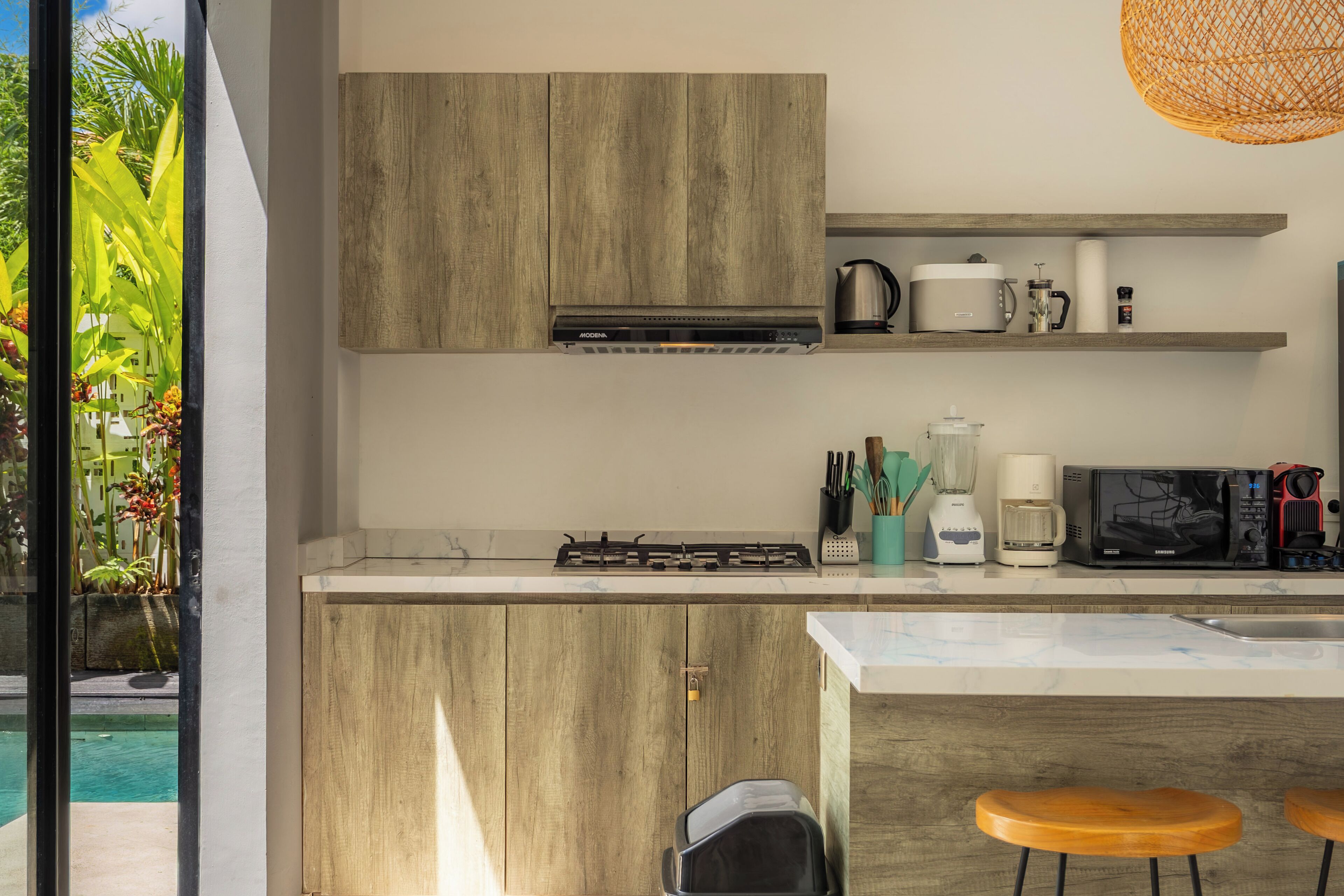 Eine moderne Küche mit Holzausstattung, einem Gasherd, einer Mikrowelle und einer Kaffeemaschine.