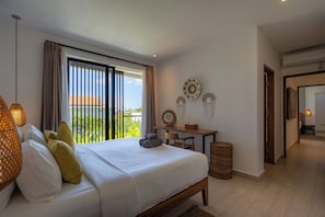 Un dormitorio con cama, escritorio, silla, cesto de basura y vistas a zonas verdes.