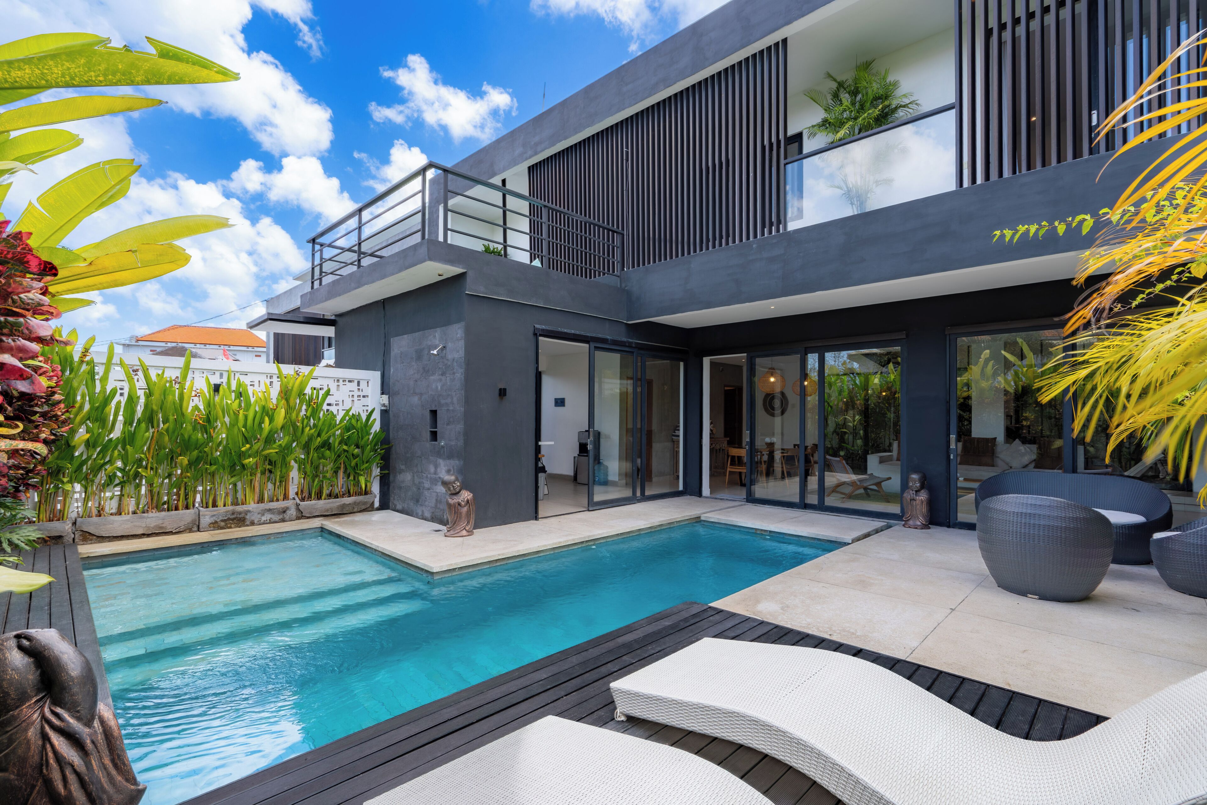 A modern house with a swimming pool, outdoor seating, and a balcony.