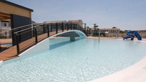 Une piscine avec un pont en arc de cercle et un toboggan bleu.