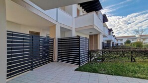 A modern residential building with a gated entrance, tiled flooring, and a well-maintained garden. - Lovely Apartment Overlooking the Pool in Bibione (San Michele al Tagliamento)