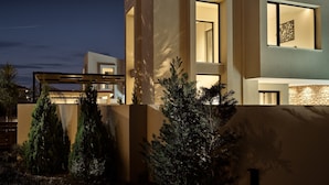Una casa moderna de dos pisos con ventanas amplias y un balcón.