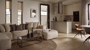 Una sala moderna con sofá, reposapiés, mesa de centro y vistas a la cocina.