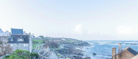 A coastal town with stone buildings, a view of the sea, and a clear sky.