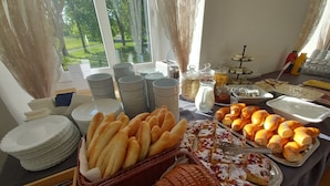 A buffet table with various breads, pastries, and condiments.