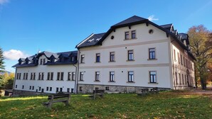 A large, multi-story building with a symmetrical facade, multiple windows, and a stone base.