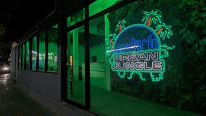 Un edificio con un letrero de neón que dice "URBAN JUNGLE" y puertas de cristal.