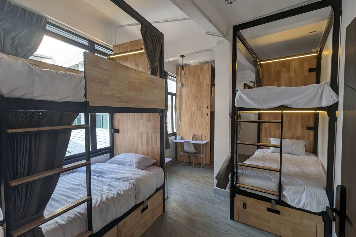 Une petite chambre avec des lits superposés, un petit bureau et une chaise.