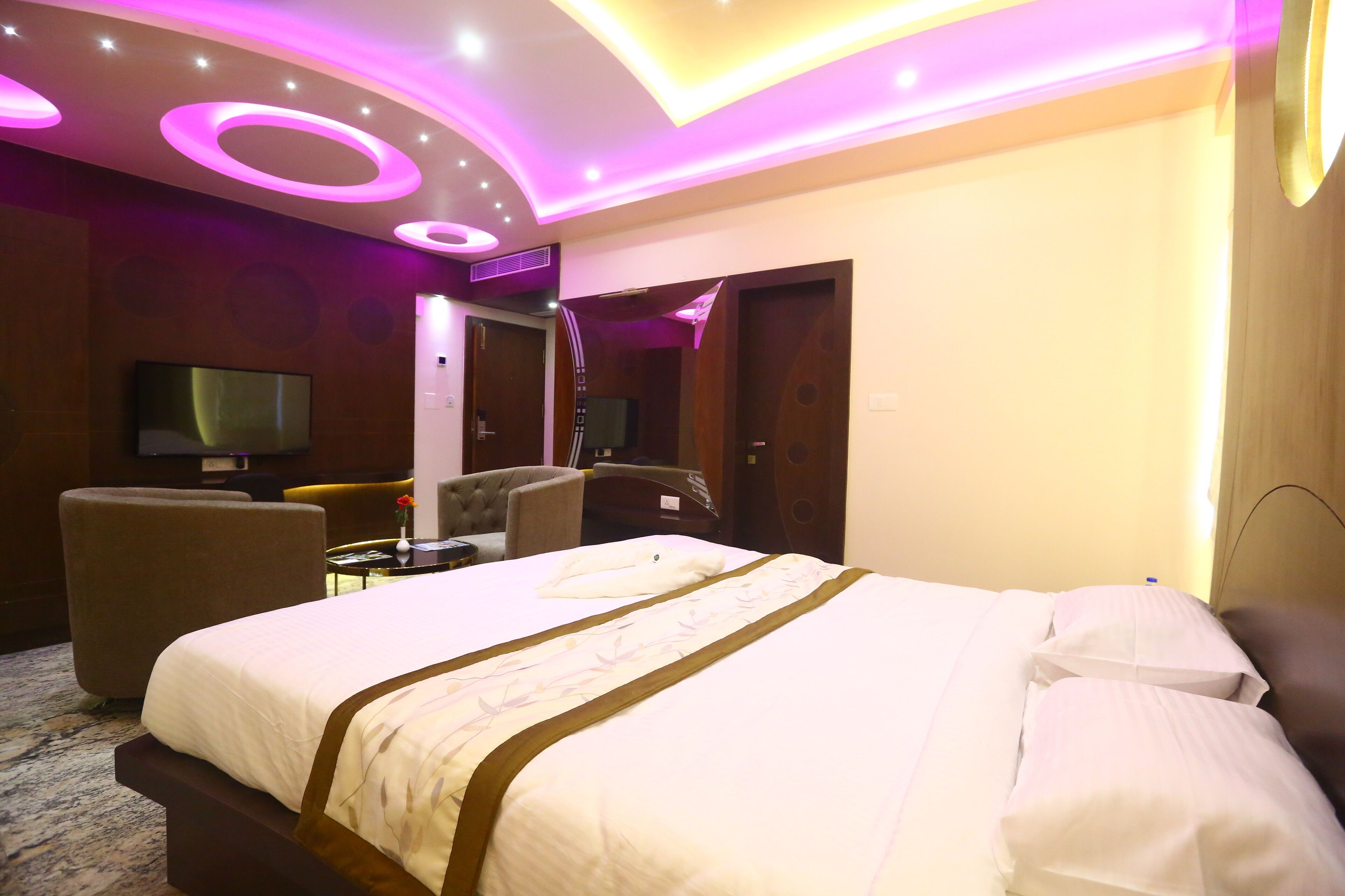 Habitación de hotel con una cama grande, un televisor de pantalla plana, un sofá y una mesita.
