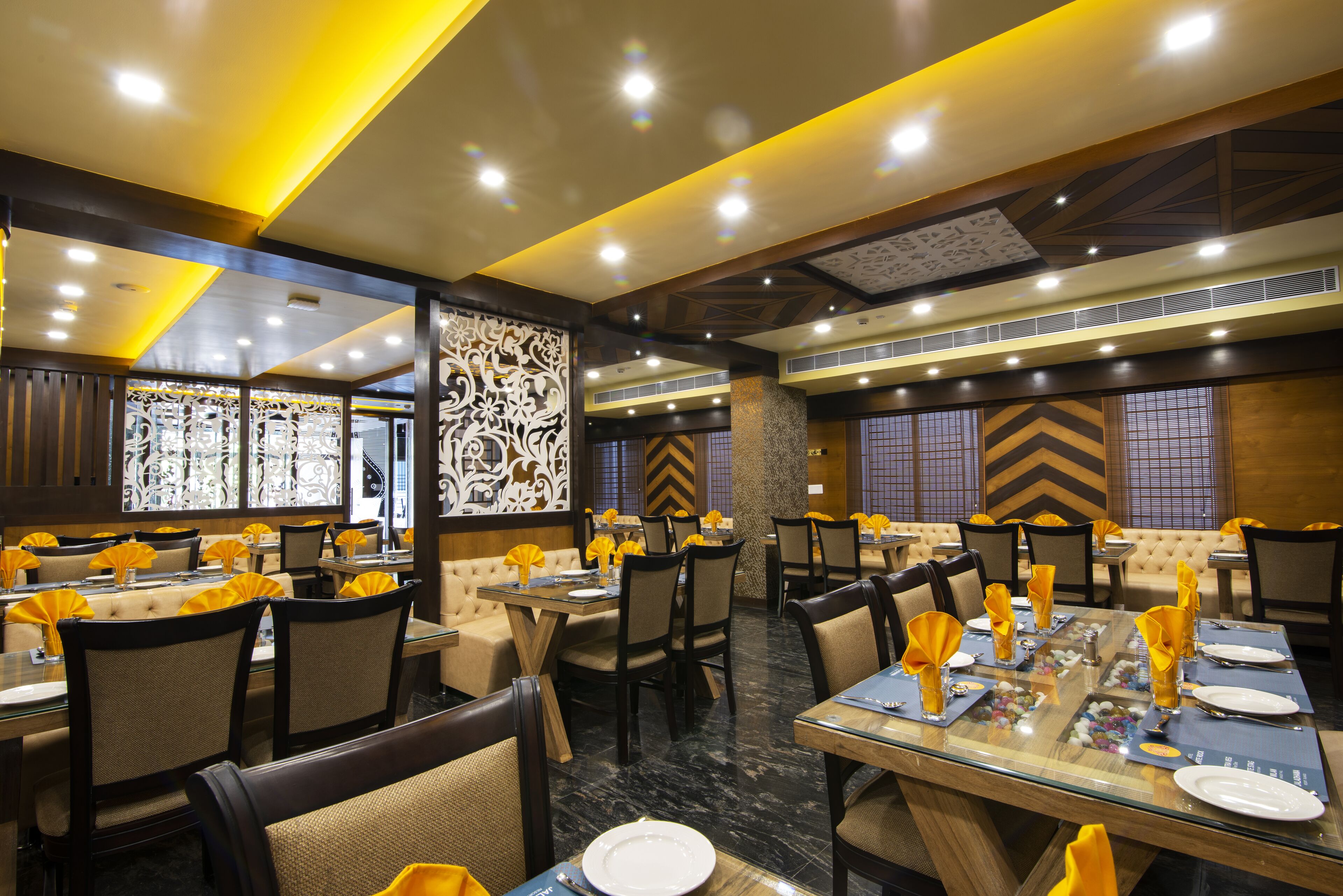 A restaurant with multiple dining tables, chairs, and a decorative wall.