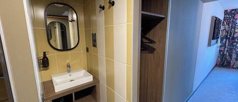 Un baño moderno con lavamanos blanco, espejo y tocador de madera.