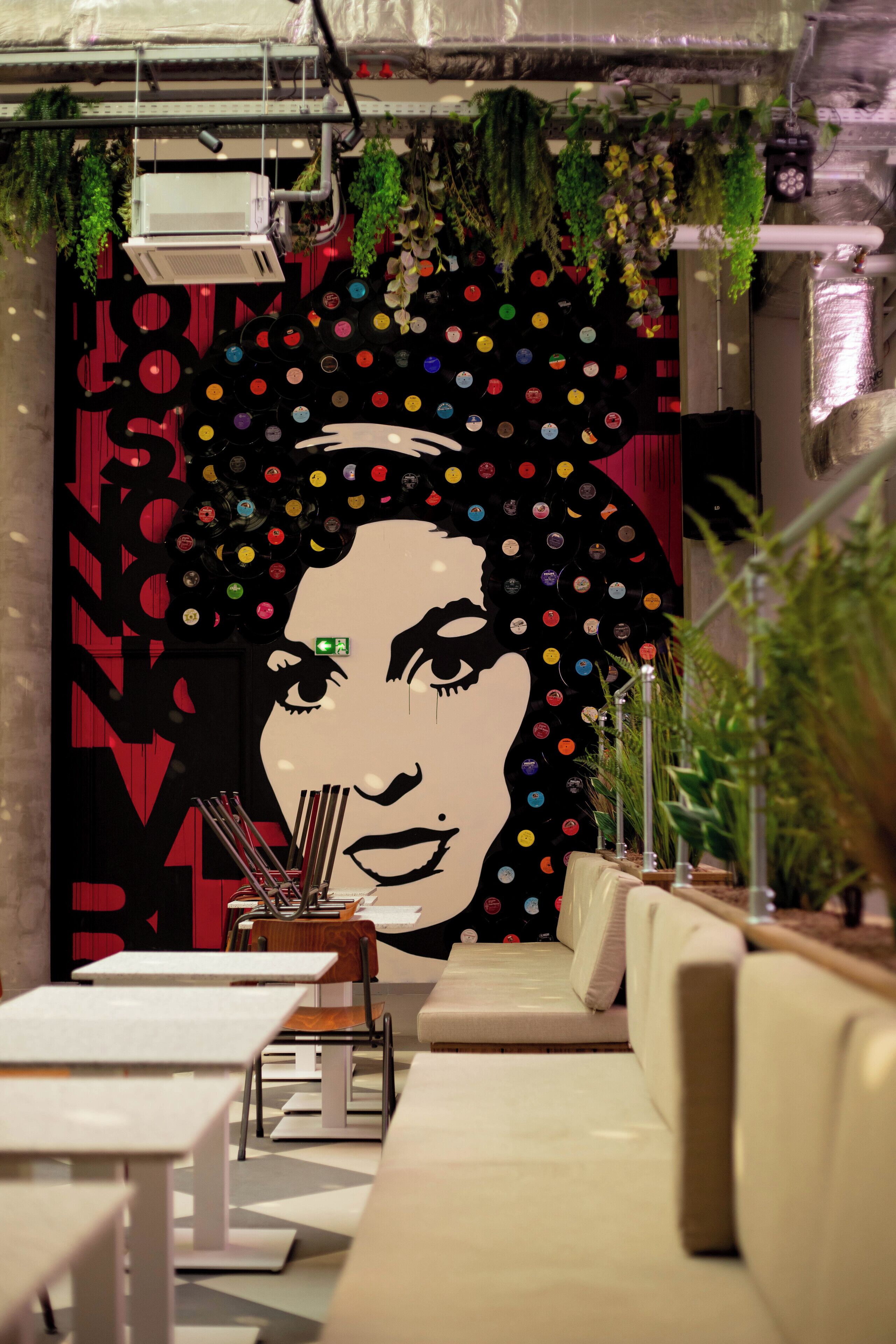 Decoração moderna com um grande mural na parede, áreas de estar e plantas em vasos.