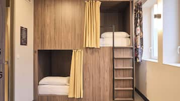 Dormitorio con literas, pared de madera, escalera y ventana con cortinas.