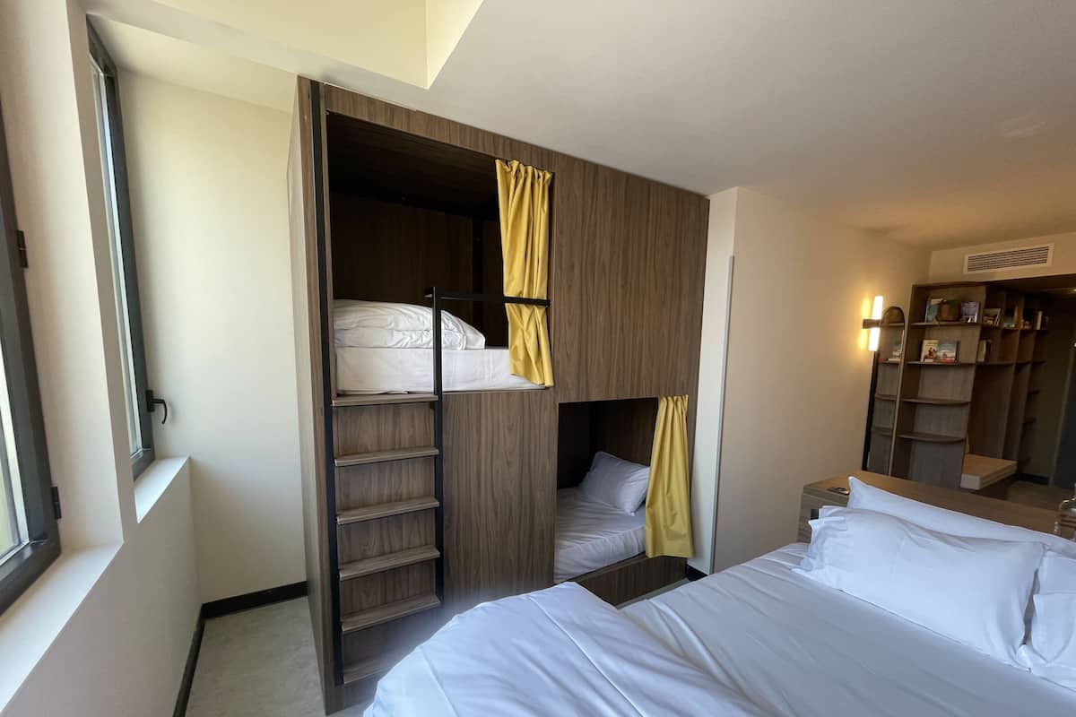 Een hotelkamer met een stapelbed, een garderobe en een nachtkastje.