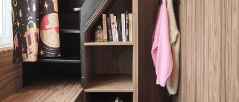 Una habitación compacta con una escalera de madera, un pequeño espacio de descanso con una mesa y una estantería.