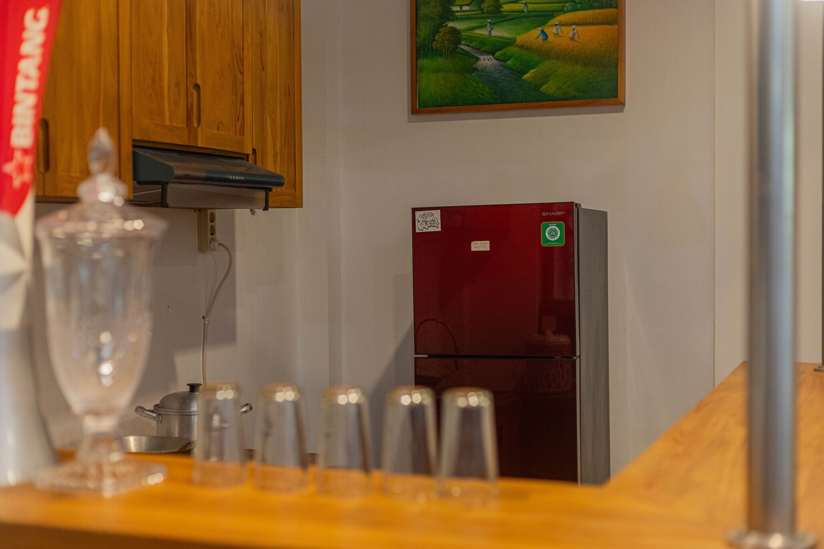 A kitchen with wooden cabinets, a red refrigerator, and a painting on the wall.