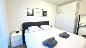 A neatly arranged hotel room with a bed, a nightstand, and a wardrobe. - Elegante Unterkunft in Stadtnähe (Adliswil)