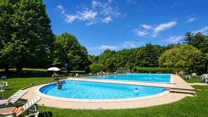 A swimming pool with a surrounding deck, surrounded by trees and grassy areas. - France Apartment With Garden, Pool & Tennis (Ispra)