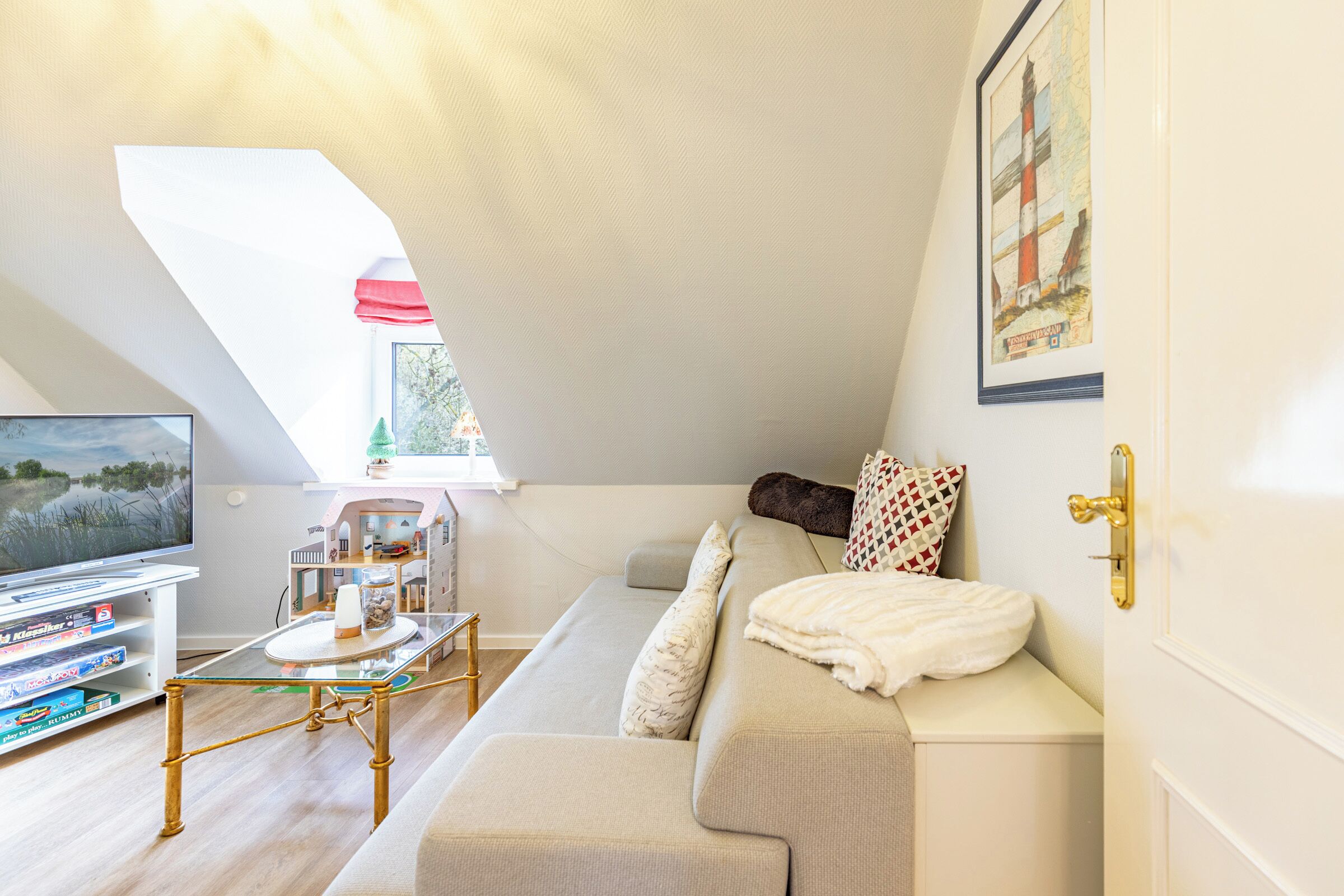 A cozy living room with a sofa, a coffee table, a television, and a bookshelf.