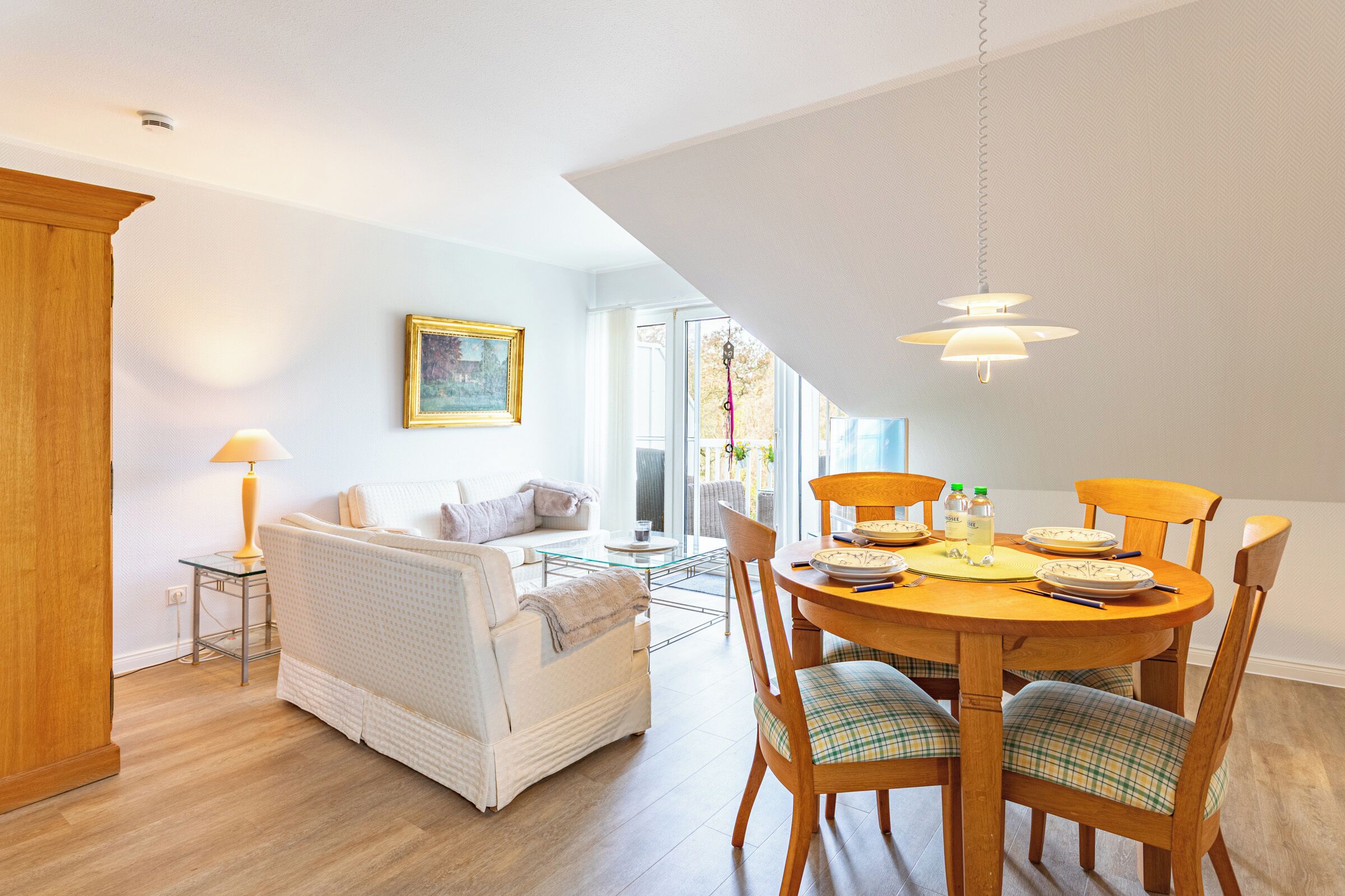 Un espace repas comprenant une table ronde, des chaises et un luminaire suspendu.