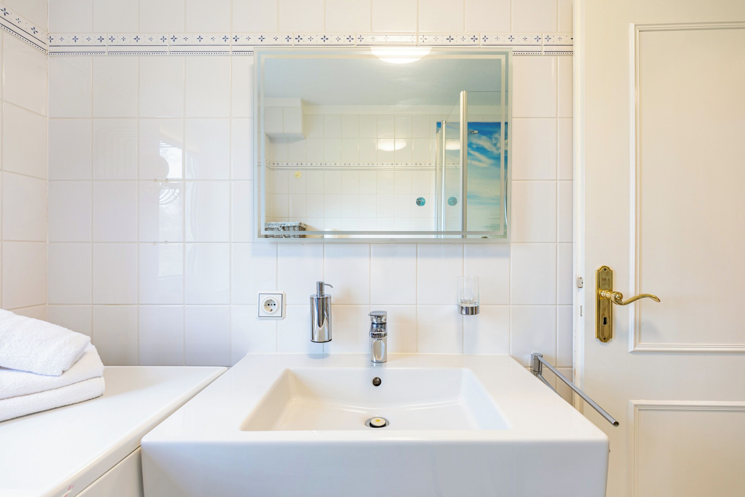 Ein Badezimmer mit einem weißen Waschbecken, einem Spiegel und einer Dusche.