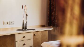 A bedroom with a wooden dresser, a bedside table, and a nightstand.