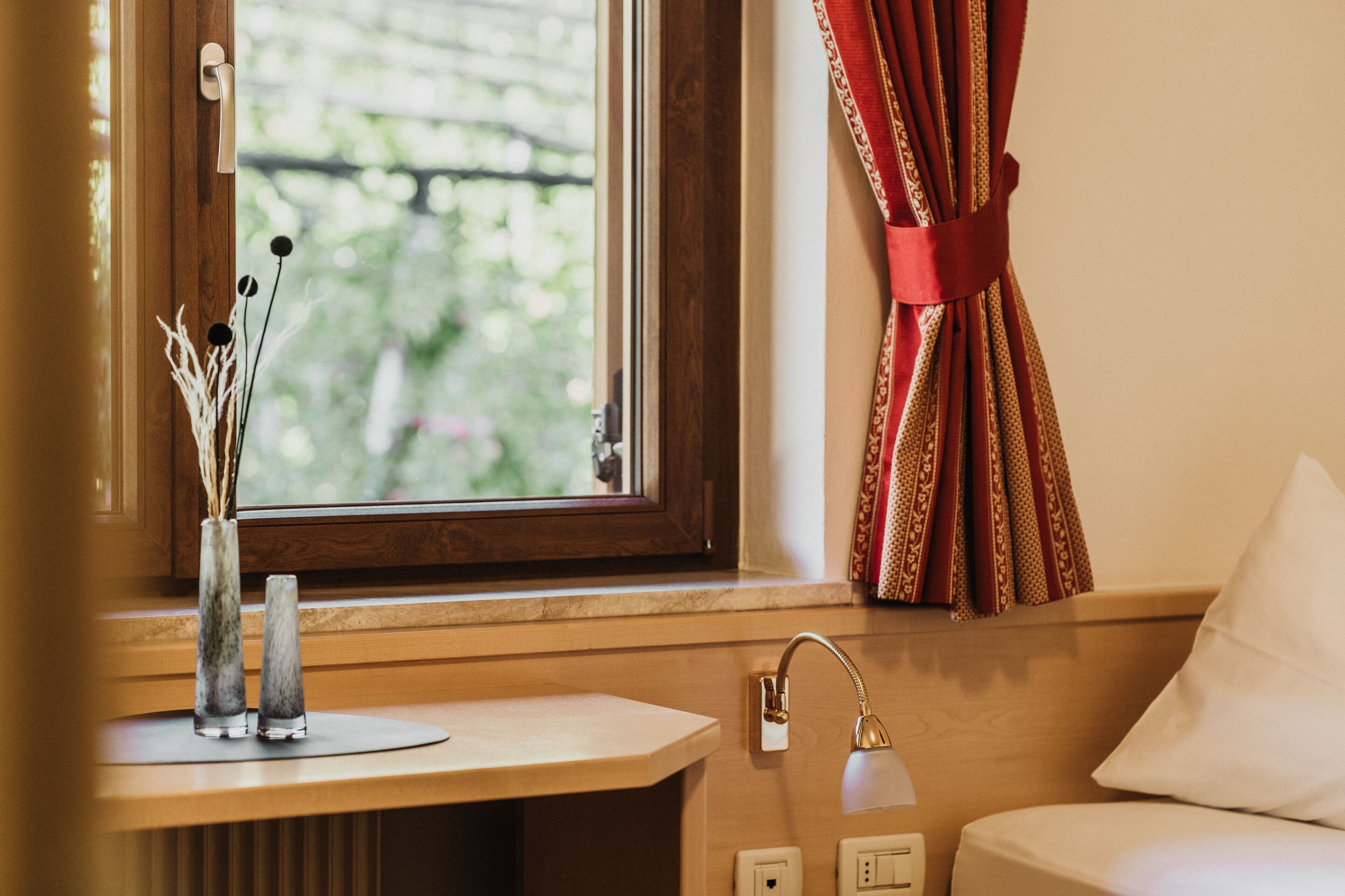 A bathroom with a wooden vanity, a window with curtains, and a sink.