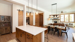 A spacious kitchen with a large island, wooden cabinets, and pendant lighting. - Luxury Condo with Private Hot Tub: Alpenglow Chalet (Fraser)