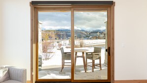 A room with a sliding glass door leading to a snowy outdoor area with a table and chairs. - Luxury Condo with Private Hot Tub: Alpenglow Chalet (Fraser)