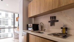 A modern kitchen with wooden cabinets, a white countertop, a sink, and a stove. - w* | Charming loft in the heart of Santa Barbara (Bogotá)