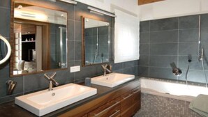 Un bagno moderno con due lavabi, un ampio specchio e una vasca da bagno.