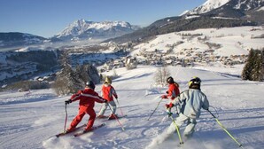 Sciatori su una pista innevata, con un paese sullo sfondo.
