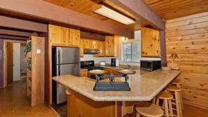 A kitchen with wooden cabinets, a stainless steel refrigerator, a stove, a microwave, and a granite countertop. - Tree Top Villa By Destination Big Bear:Upper Moonridge! Decks! Pool/Ping Pong Table! Foosball! (Big Bear City)