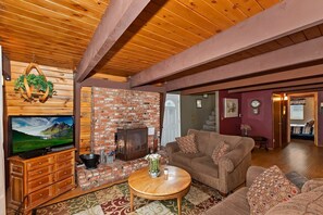 A cozy living room with a brick fireplace, a television, and a comfortable couch.