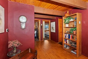 A hallway with a wooden bench, a clock, and a bookshelf with books and plants.