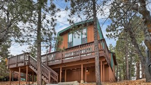 A two-story cabin with a wooden deck and stairs leading to a balcony. - Tree Top Villa By Destination Big Bear:Upper Moonridge! Decks! Pool/Ping Pong Table! Foosball! (Big Bear City)
