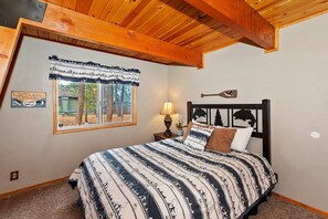 A bedroom with a bed, a window with a view, a lamp, and a wall-mounted decoration.