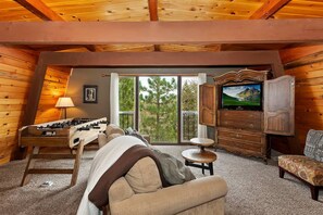 A cozy room with a foosball table, a sofa, a television, and a dresser.