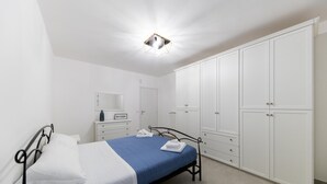 Een slaapkamer met een bed, een witte kledingkast en een nachtkastje.
