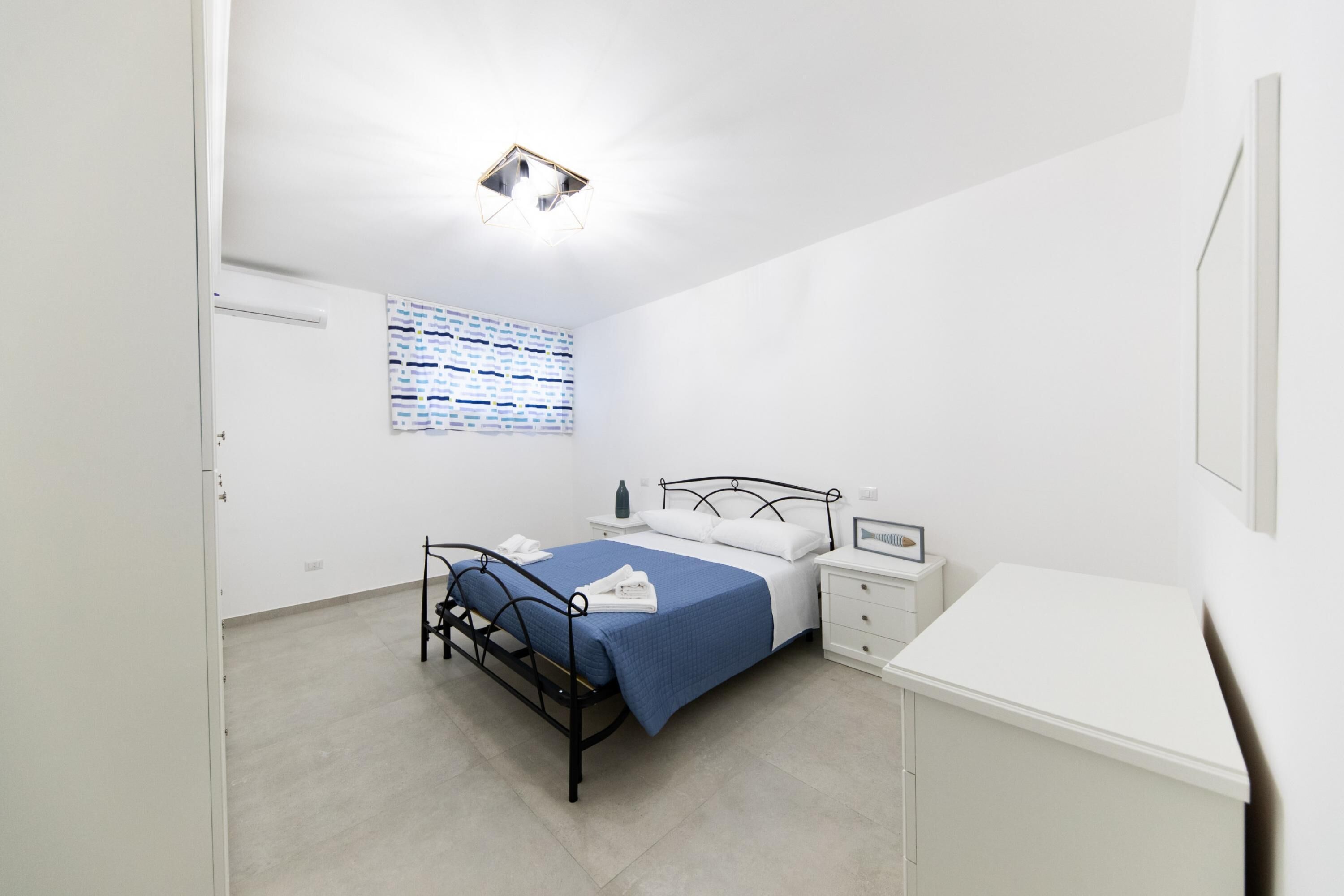 Un dormitorio con cama, mesita de noche y ventana con persianas.