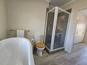 A bathroom with a bathtub, toilet, and a glass-enclosed shower area. - Dorphene 304 by CTHA (Cape Town)