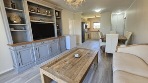 Un ampio soggiorno con un tavolino in legno, una televisione e un lampadario.