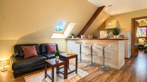 Un salon confortable avec un canapé, une petite table et une cuisine équipée d’un bar.