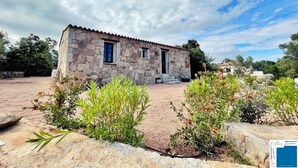 A stone building with a tiled roof, surrounded by greenery and a gravel path. - Petite Bergerie Avec Piscine Privée & Climatisation (San-Gavino-Di-Carbini)