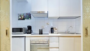 A modern kitchen with white cabinets, a stainless steel range hood, a microwave, a coffee maker, and a dishwasher. - Elegant Apartment Near Trevi Fountain (Roma)