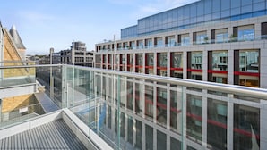 A modern building with a glass facade and a metal balcony railing. - Sleek 2BD Flat W/terrace - 2 Mins From Farringdon! (London)
