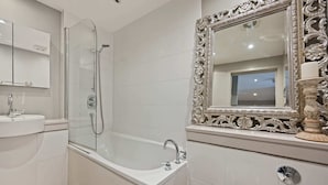 A modern bathroom with a glass-enclosed shower, a large mirror with an ornate frame, and a white sink. - Sleek 2BD Flat W/terrace - 2 Mins From Farringdon! (London)