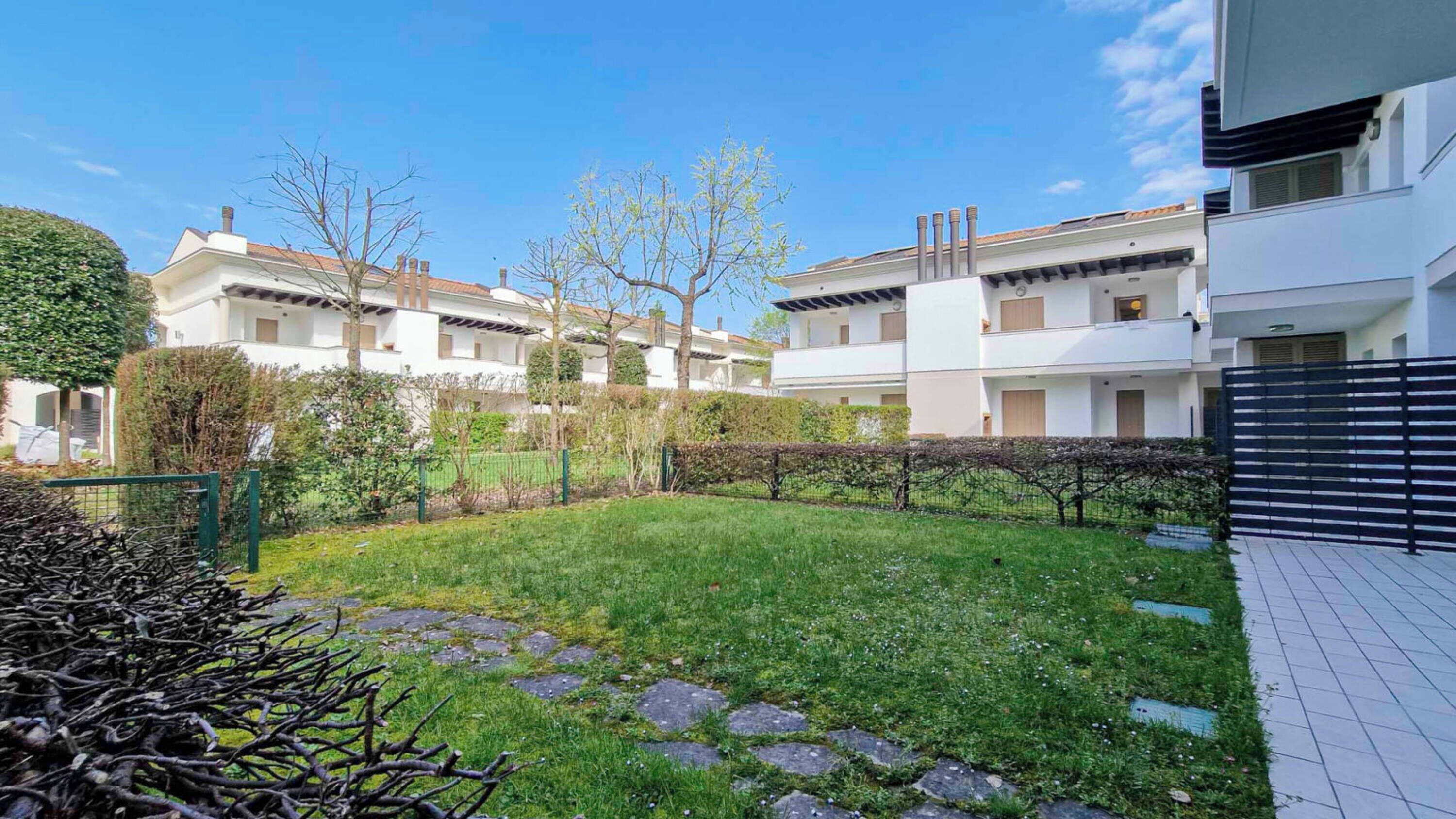 Zona residencial com edifícios modernos, um pátio ajardinado e um jardim murado.