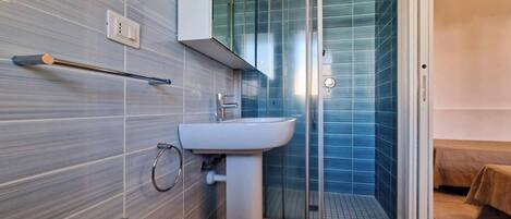 A modern bathroom with a white sink, a glass shower enclosure, and a towel rack.